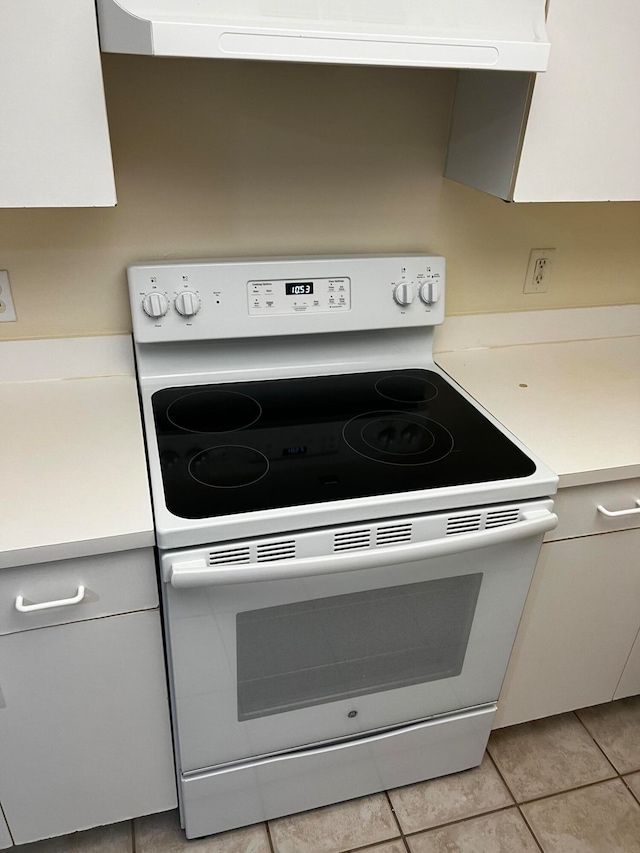 kitchen featuring white cabinets, white range with electric cooktop, light tile patterned flooring, and extractor fan