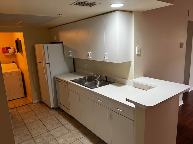 kitchen featuring washer / dryer, dishwasher, light tile patterned flooring, sink, and kitchen peninsula