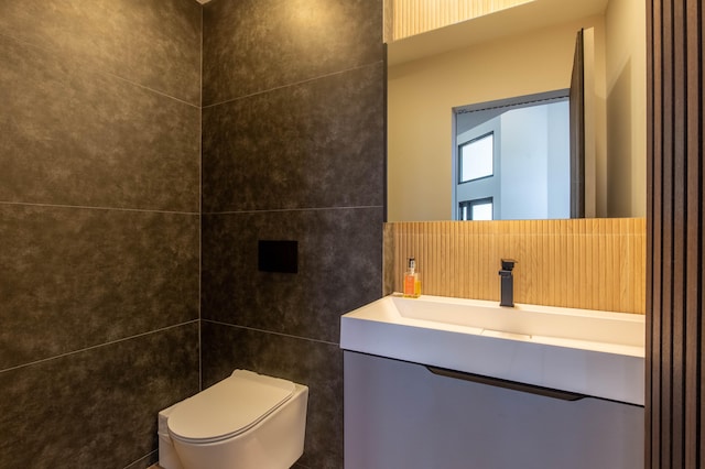 bathroom with tile walls, vanity, and toilet