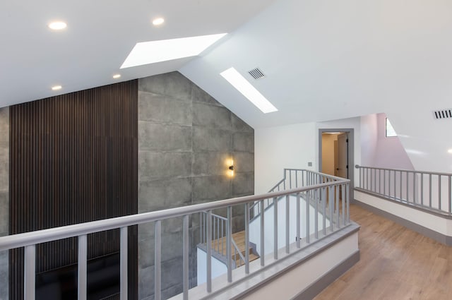 corridor featuring lofted ceiling with skylight and hardwood / wood-style flooring