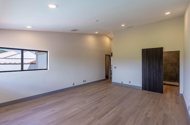 unfurnished room featuring lofted ceiling and light hardwood / wood-style flooring