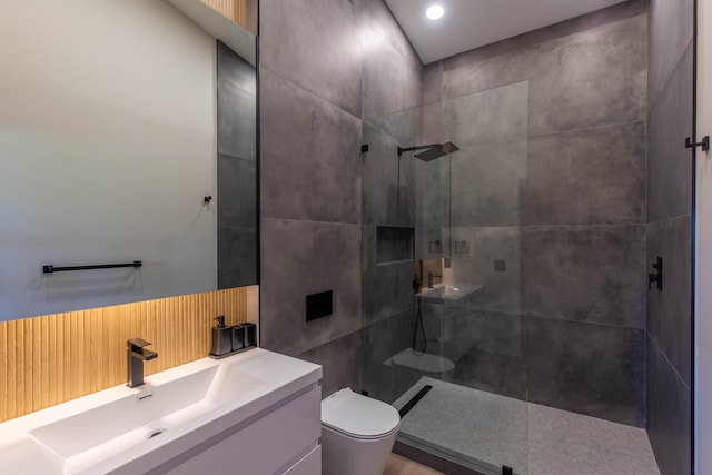 bathroom featuring a tile shower, vanity, and toilet