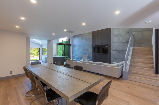 dining space with vaulted ceiling and light hardwood / wood-style flooring