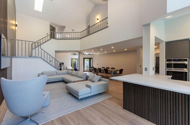 living room with light hardwood / wood-style floors and high vaulted ceiling