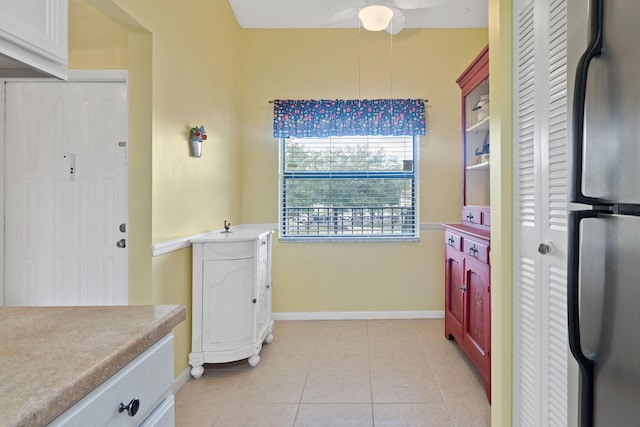 kitchen featuring white cabinets, light tile patterned flooring, and stainless steel fridge