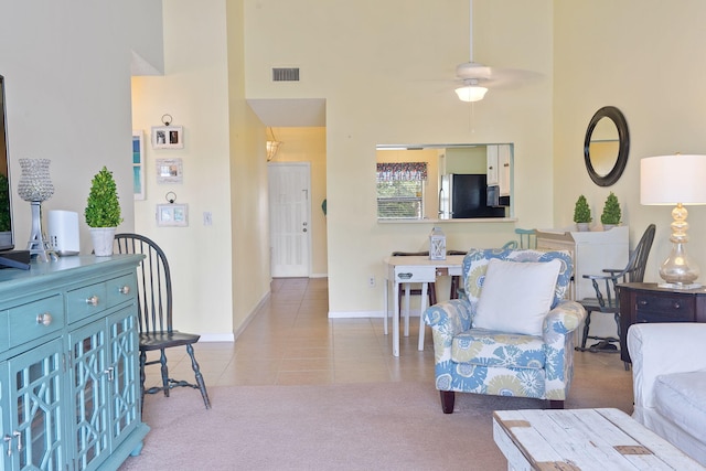 living room featuring light carpet, a high ceiling, and ceiling fan