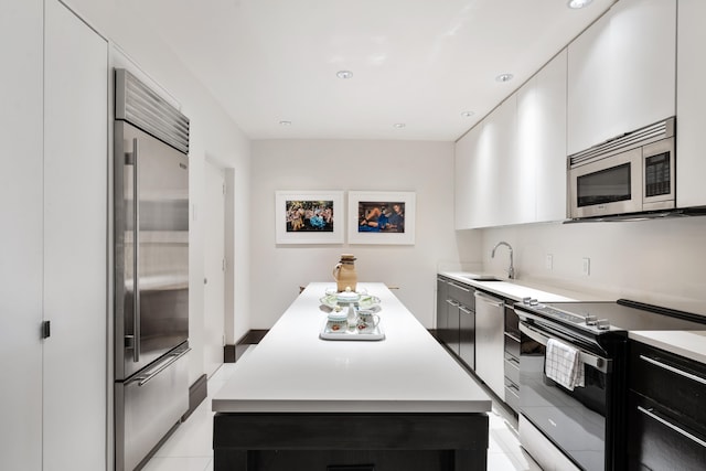 kitchen featuring sink, a kitchen island, stainless steel appliances, white cabinets, and light tile patterned floors