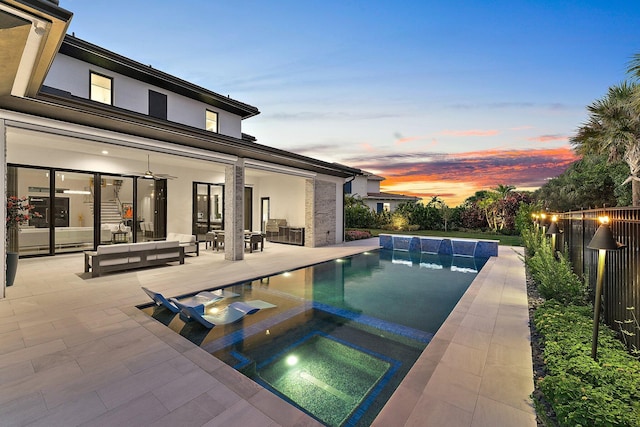 pool at dusk with a patio and an in ground hot tub