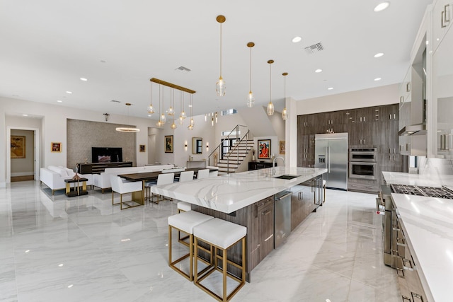 kitchen featuring a spacious island, hanging light fixtures, stainless steel appliances, dark brown cabinetry, and white cabinets