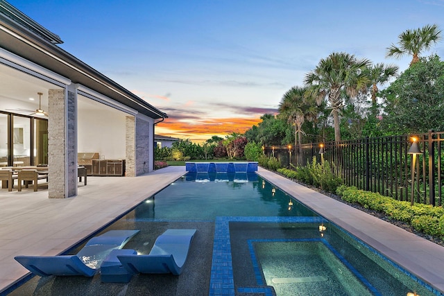 pool at dusk with a patio and pool water feature