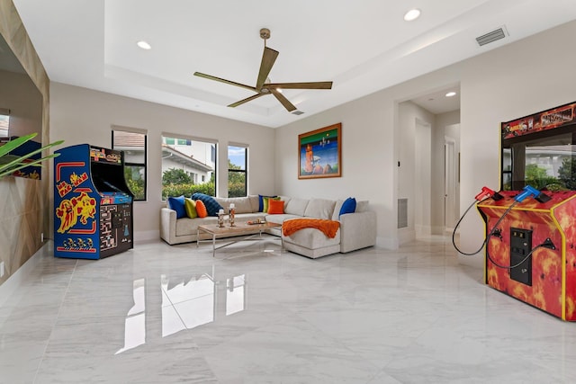 living room with a raised ceiling and ceiling fan