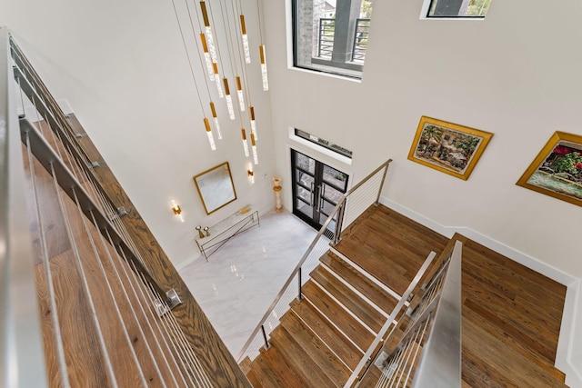 staircase featuring french doors, hardwood / wood-style flooring, and a towering ceiling