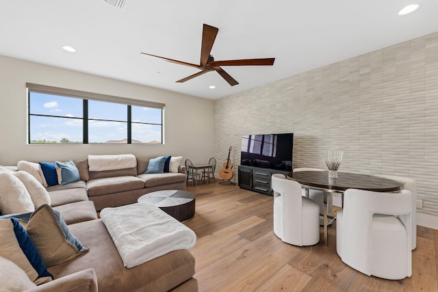 living room with light hardwood / wood-style floors, tile walls, and ceiling fan