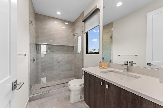 bathroom with toilet, vanity, and a shower with door