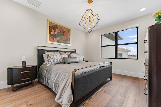 bedroom with light hardwood / wood-style floors and an inviting chandelier