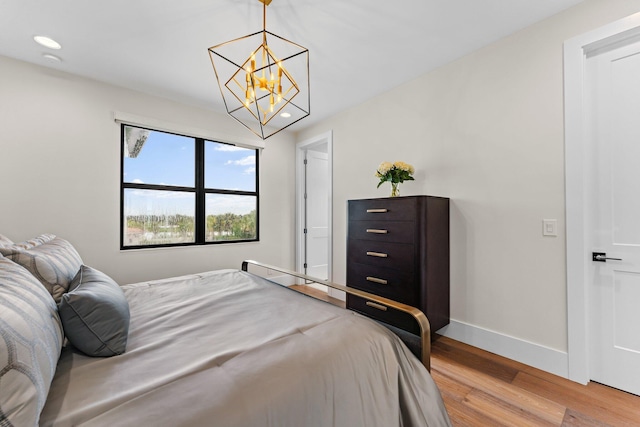 bedroom with light hardwood / wood-style flooring and a notable chandelier