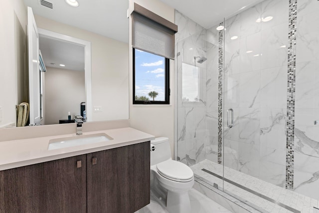 bathroom featuring toilet, vanity, and a shower with door