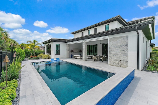 rear view of property featuring a patio area and a fenced in pool