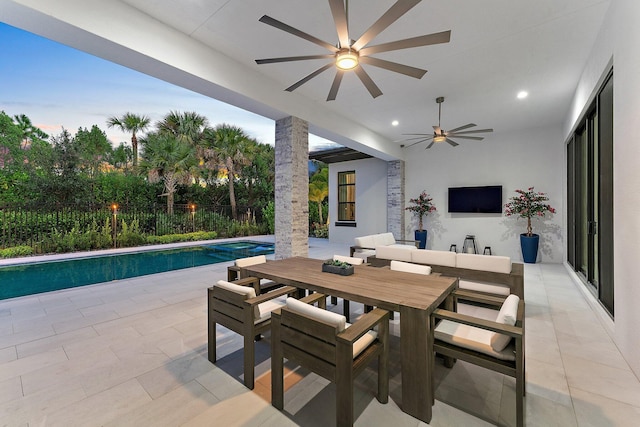 patio terrace at dusk with a fenced in pool and ceiling fan