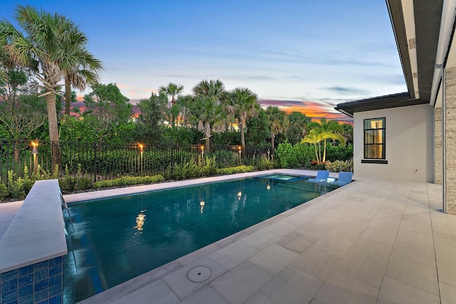 pool at dusk with a patio and pool water feature