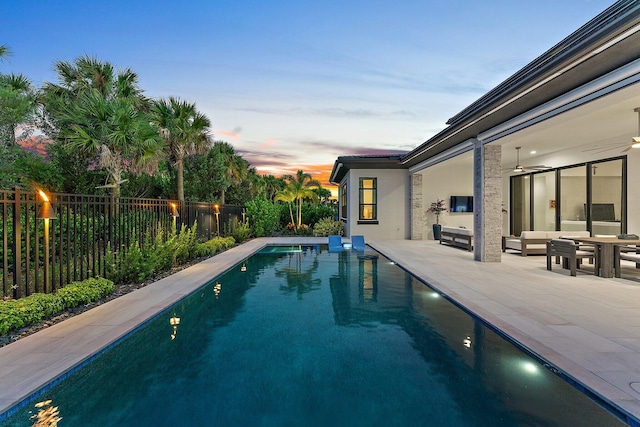 pool at dusk featuring a patio area and ceiling fan