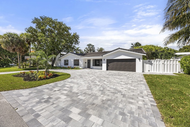 view of front facade featuring a gate, a front yard, a garage, and curved driveway