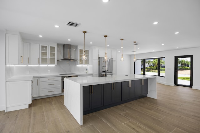 kitchen with freestanding refrigerator, white cabinets, wall chimney exhaust hood, visible vents, and recessed lighting