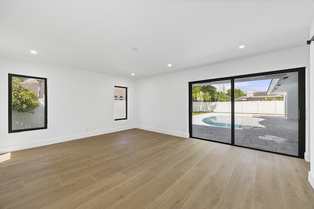 unfurnished room featuring baseboards, wood finished floors, and recessed lighting