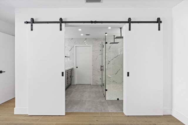 bathroom with recessed lighting, wood finished floors, visible vents, and a marble finish shower