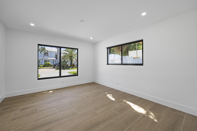 unfurnished room with recessed lighting, wood finished floors, and baseboards
