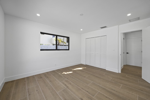 unfurnished bedroom featuring baseboards, wood finished floors, and visible vents
