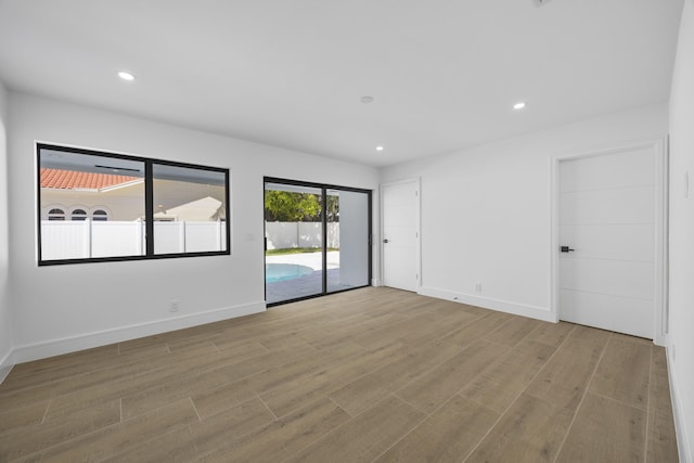 empty room featuring baseboards, wood finished floors, and recessed lighting
