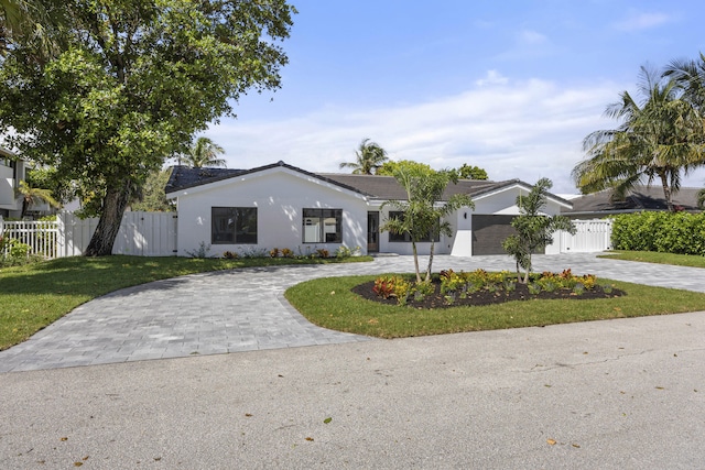 view of front of house featuring fence, a front yard, curved driveway, and stucco siding