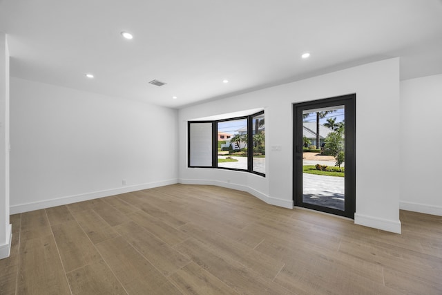 unfurnished room featuring recessed lighting, wood finished floors, visible vents, and baseboards