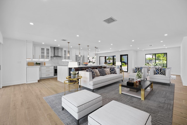 living room with recessed lighting, visible vents, light wood finished floors, and baseboards