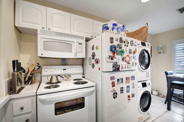 kitchen featuring light tile patterned floors, white appliances, white cabinets, light countertops, and stacked washer and clothes dryer