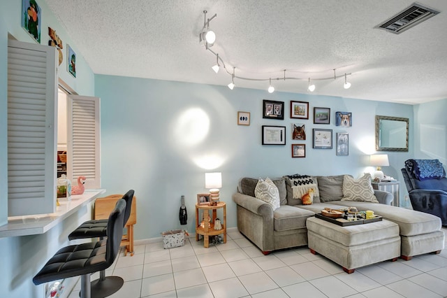 living area featuring visible vents, a textured ceiling, baseboards, and light tile patterned floors