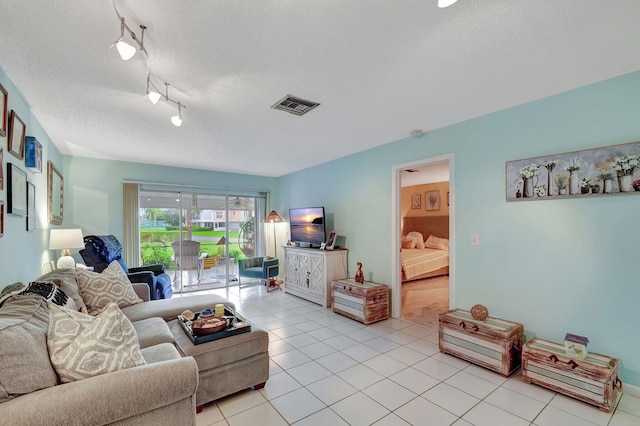 living room with light tile patterned floors, track lighting, visible vents, and a textured ceiling