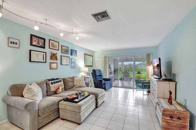 living room featuring rail lighting, visible vents, a textured ceiling, and light tile patterned floors