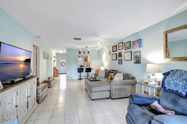 living room featuring a textured ceiling, light tile patterned flooring, and visible vents