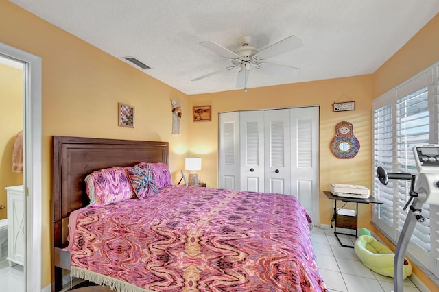 bedroom with visible vents, ceiling fan, a textured ceiling, a closet, and light tile patterned flooring