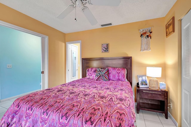 bedroom featuring visible vents, light tile patterned flooring, ceiling fan, a textured ceiling, and baseboards