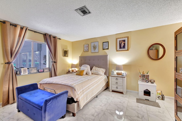 bedroom featuring a textured ceiling, marble finish floor, visible vents, and baseboards