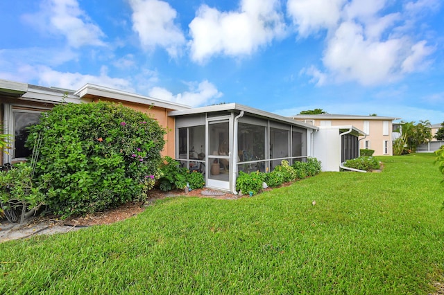 rear view of house featuring a sunroom and a lawn