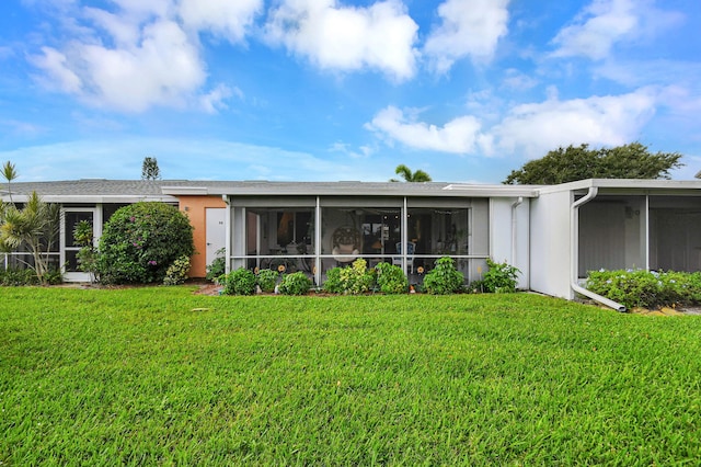 rear view of property with a sunroom and a lawn