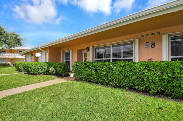 ranch-style house with a front lawn and stucco siding