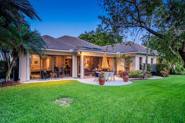 back of property with a lawn and a patio area