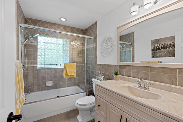 full bathroom with toilet, tile patterned flooring, tile walls, shower / bath combination with glass door, and vanity