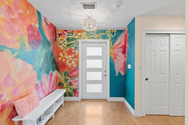 foyer with wood-type flooring, a textured ceiling, and a healthy amount of sunlight