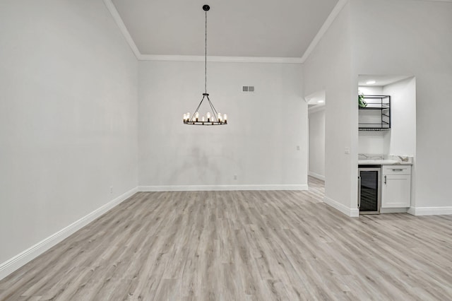 unfurnished dining area featuring light wood finished floors, visible vents, ornamental molding, and baseboards